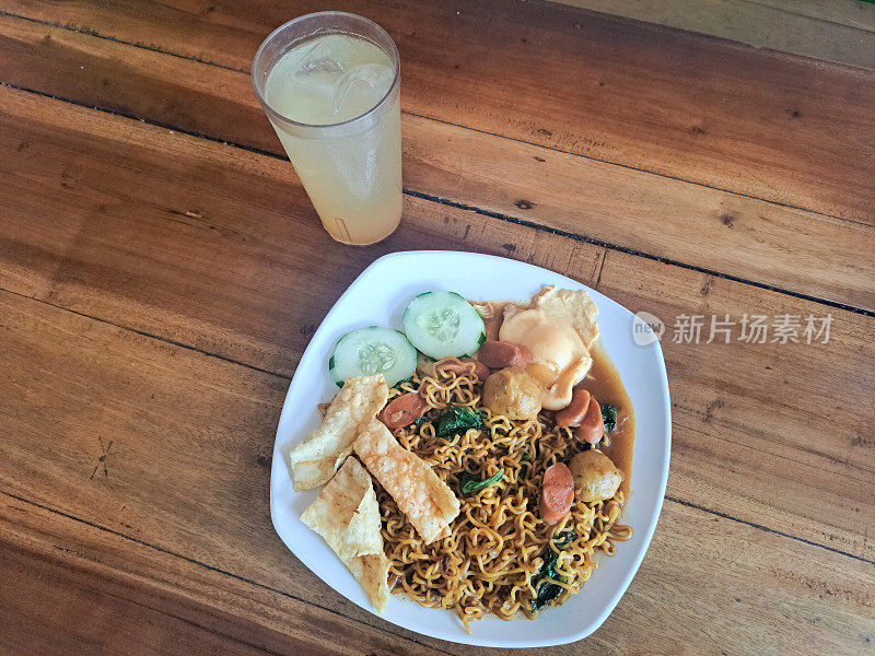 尼米克炸面或米糠尼米克配肉丸，香肠，炸饺子，黄瓜片，绿芥末和酸橙冰镇饮料。Mi Goreng Nyemek Dan Es Jeruk Nipis。食物和饮料。印尼的食物。餐厅菜单。